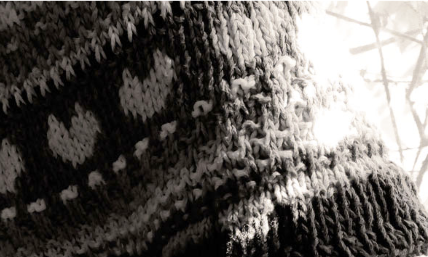 Sleeve of a knitted sweater with a heart on it.