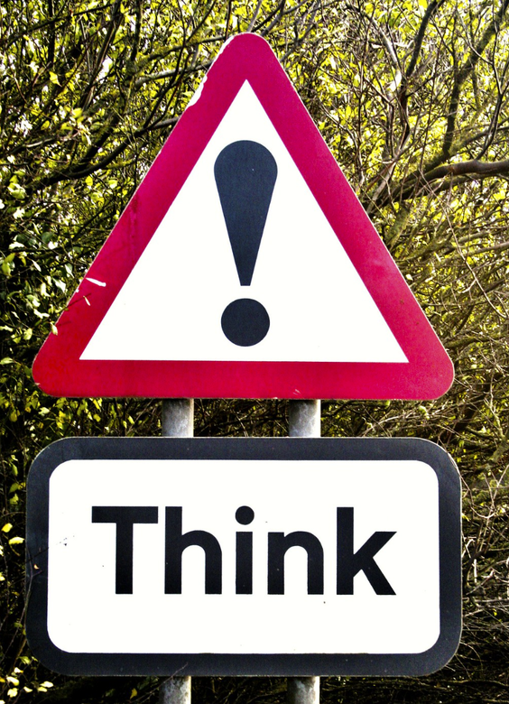 Photo of a red triangular street sign with an exclamation point in the center, with a rectangular white sign below reading
